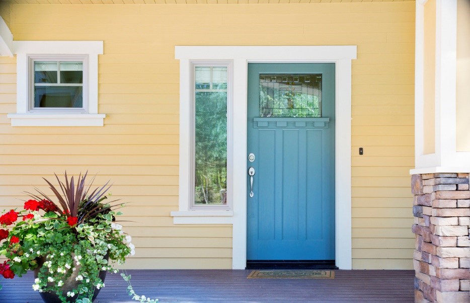 Wooden teal door on a yellow painted house front