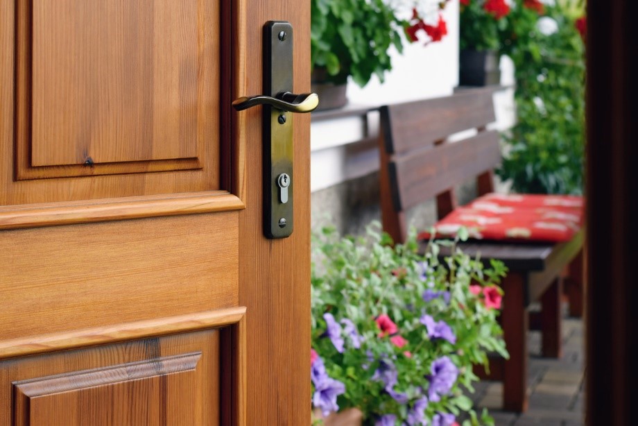 Wooden door with black handle leading to a stunning English garden