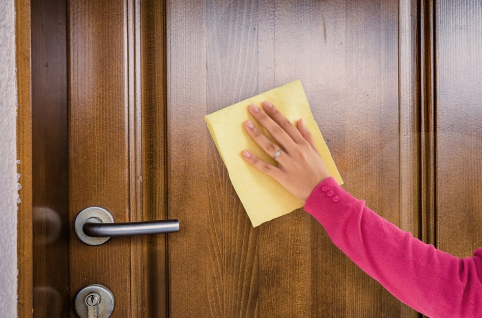 A woman cleaning an wooden door with a cloth