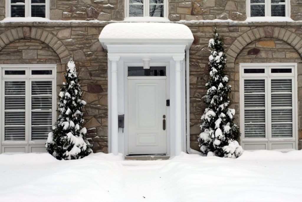 Beautiful snowy day image of a house with white wooden door