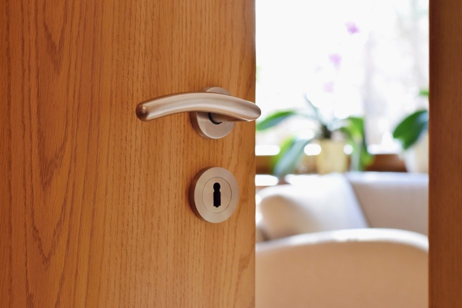 Wooden interior door with stainless steel handle opening to a living room