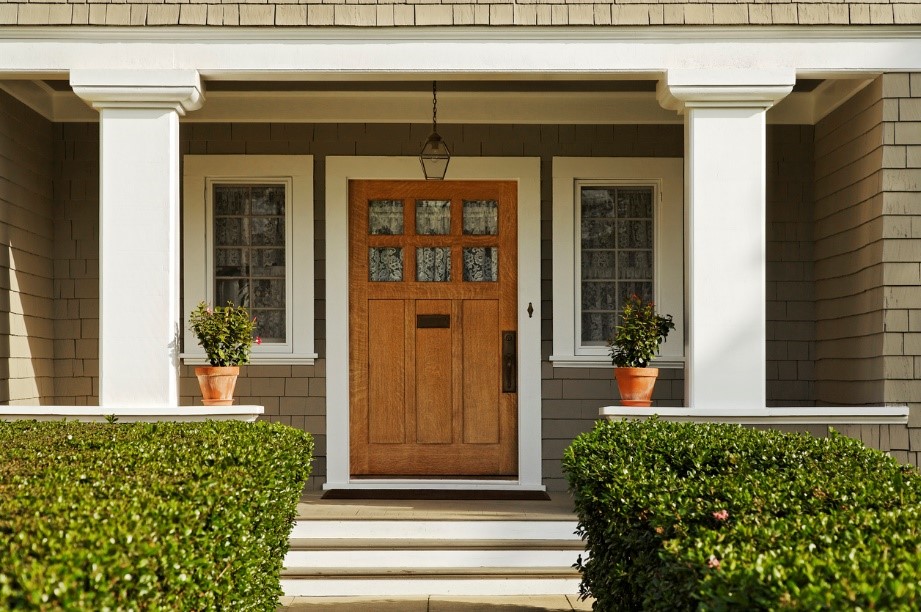 Beautiful porch with large impressive wooden door central to the image