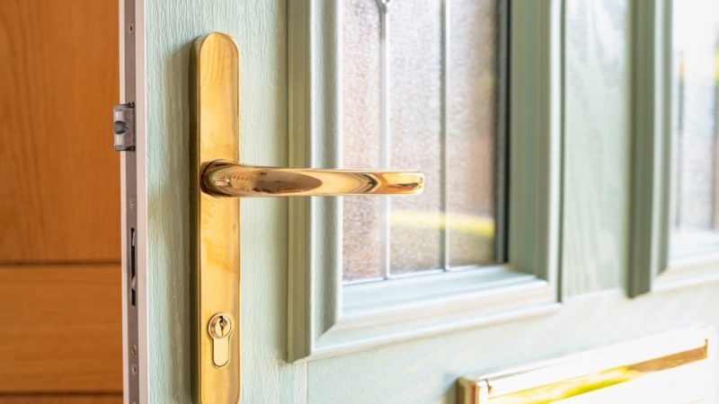 A gold door handle on a green door